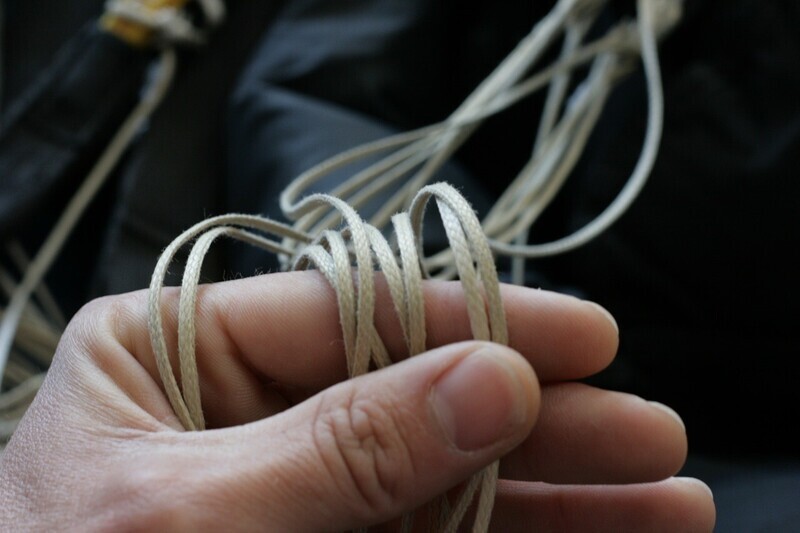 A hand holding a tangle of parachute lines